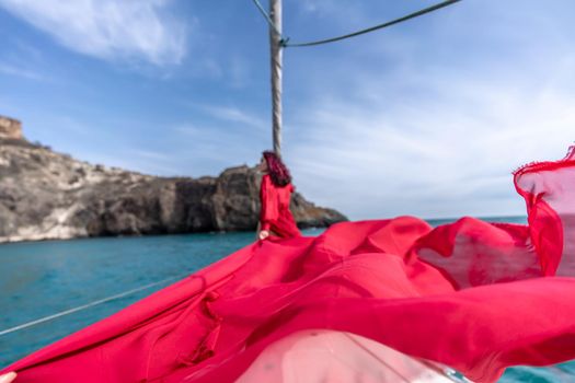 Attractive middle-aged woman in a red dress on a yacht on a summer day. Luxury summer adventure, outdoor activities