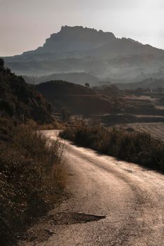 Landscape showing Montserrat mountain at the end of a path in a misty morning view