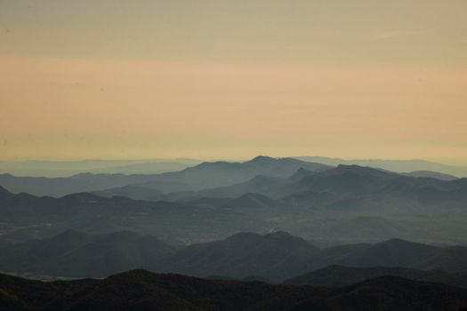 Landscape showing layers of mountains under the mist and a clear sky over them