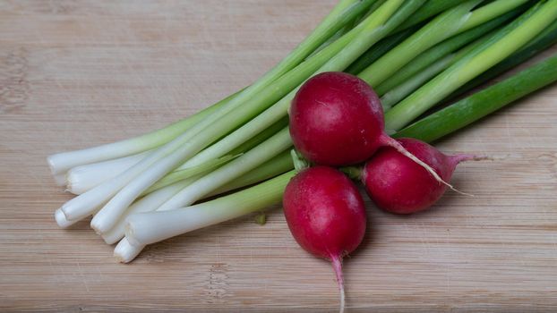 green onions and radishes close-up on a wooden background. High quality photo
