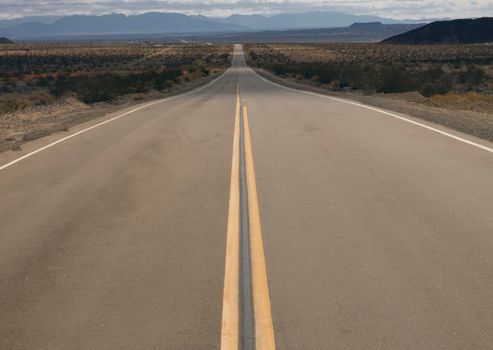 Long and straight road to the horizon under a cloudy sky