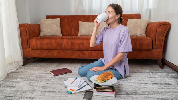 Female student drinks coffee while studying at home. High quality photo