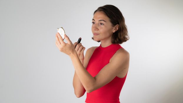 A woman looks in the mirror and paints her lips with lipstick. High quality photo