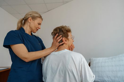 Professional doctor in uniform examines the patient during a visit to hospital ward in clinic