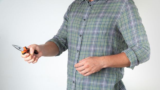 A man holds plier pliers in his right hand, gesture on a white background - home repairs. High quality photo