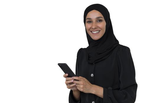 Young beautiful Muslim woman in black hijab on white background looking at camera and smiling holding phone, Arab woman using smartphone.