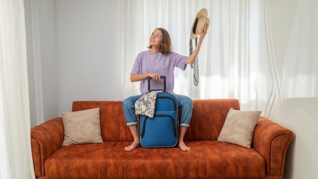 A woman packed a suitcase, sits satisfied on the couch and prepares for the trip. High quality photo