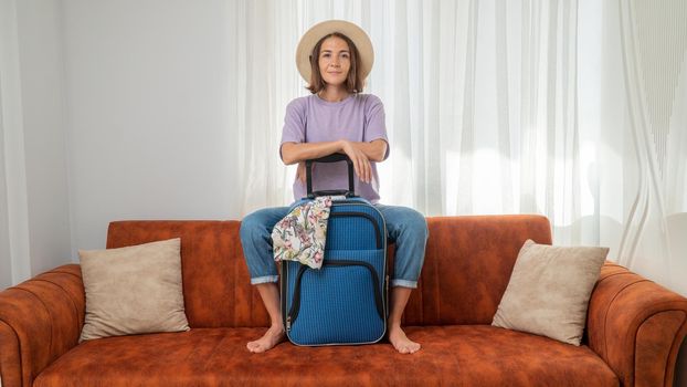 Gathering for the trip - a woman with a suitcase at home on the couch, in anticipation of the trip. High quality photo
