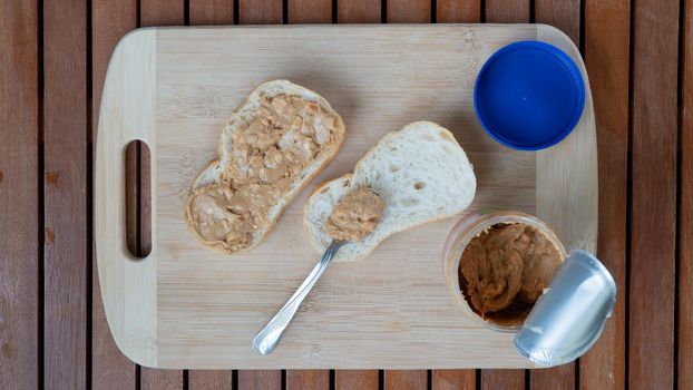 A can of peanut butter with two sandwiches on a wooden board. High quality photo