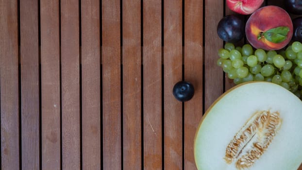 Melon, plum, grape and peach on a wooden background with space for text. High quality photo