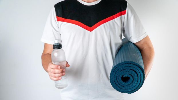 Sporty man with workout mat and bottle of water on white background. High quality photo