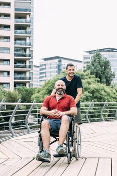 disabled man in wheelchair laughing during a walk with a friend at park, concept of friendship and integration of people with disabilities and reduced mobility problems