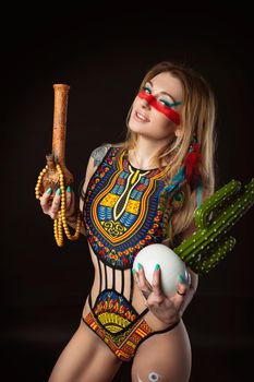 the sexy hippie girl posing with bong for smoking marijuana in a bright swimsuit on a dark background