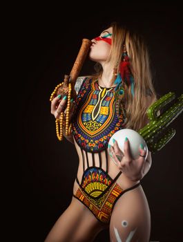 the sexy hippie girl posing with bong for smoking marijuana in a bright swimsuit on a dark background