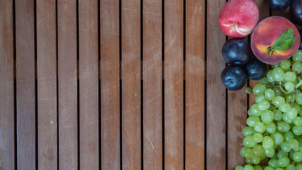 Fruit mix of grapes, plums and peaches on a background of wood. High quality photo