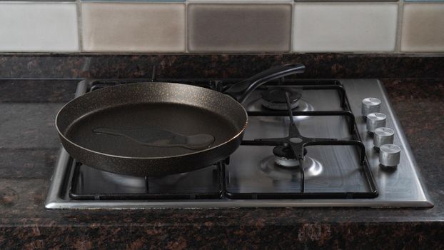 A frying pan with poured vegetable oil is on a gas stove. High quality photo