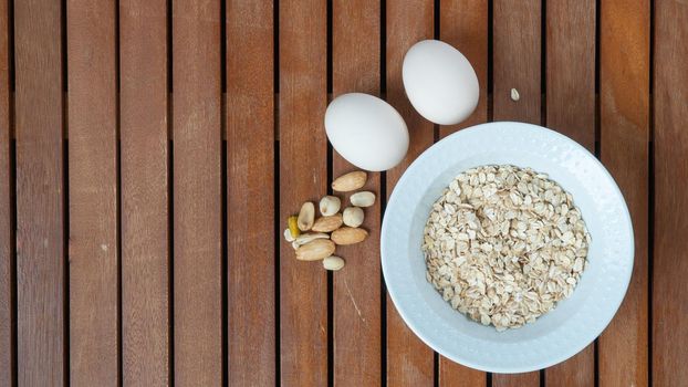 Breakfast oatmeal, nuts and boiled eggs on a wooden background table. High quality photo