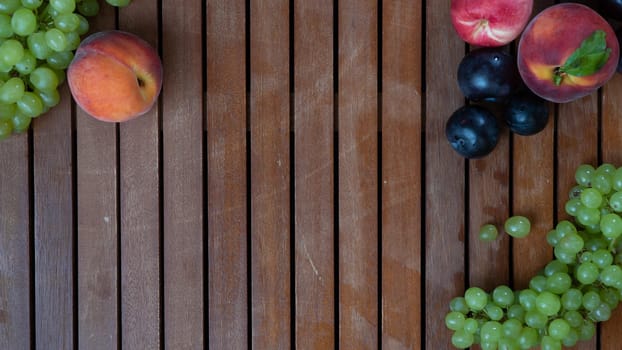 Fruits on a wooden background with space for inscription - grapes, peach, plum. High quality photo