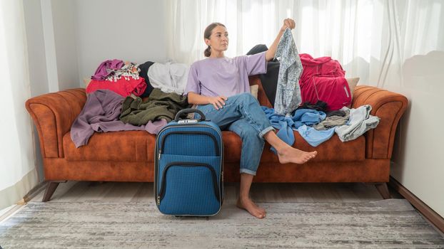 Woman with suitcase and scattered belongings, choice of clothes. High quality photo