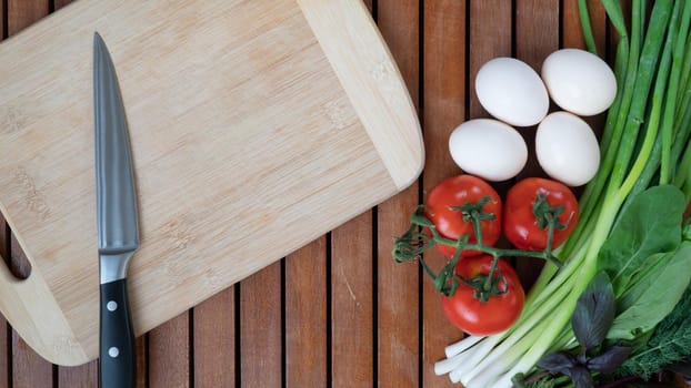Tomato, green onion, basil arugula dill, eggs on a wooden background