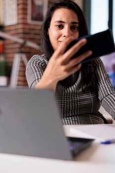 Young adult using smartphone to take pictures on work break, doing remote startup job at home. Holding mobile phone and taking photos, working on freelance and attending online lesson.