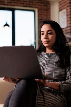 Indian person working on laptop at home, attending online class lesson or doing remote business work on computer. Using wireless pc to browse internet for research, virtual webinar.