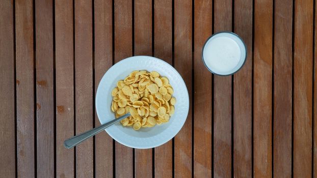 Corn flakes and milk for breakfast on a wooden background. High quality photo