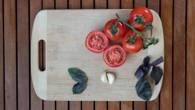 tomatoes, basil and garlic on a cutting board wooden background. High quality photo
