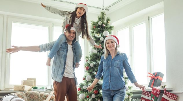 Christmas. Family. Happiness. dad, mom and daughter in Santa hats looking at camera and smiling