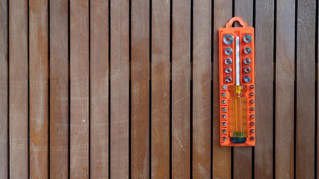 Set of bits and screwdrivers in orange case on wooden background. High quality photo