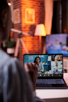 Young businesspeople having discussion on videoconference, telecommunications and remote teamwork concept. African american female team lead chatting with coworkers using videocall software and laptop