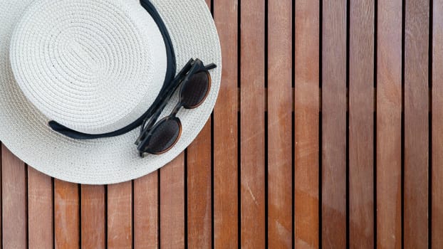 Straw women's hat with ribbon and glasses on a wooden background place for text