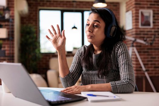 Female freelancer attending videocall conference on laptop, talking to people at online business meeting with webcam. Using remote videoconference call to chat on telecommunications at home.