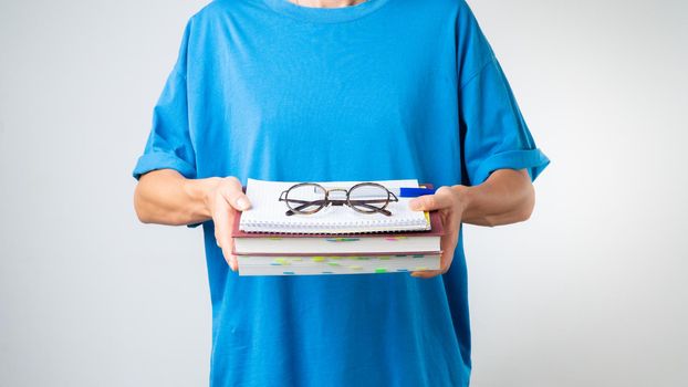 A student holds a stack of books and notebooks in her hands, glasses - gets knowledge. High quality photo