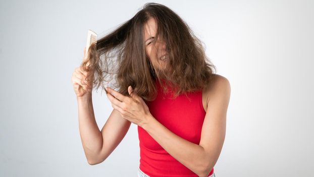 It hurts a woman when combing naughty, tangled hair - pulling out a comb and pulling her hair. High quality photo