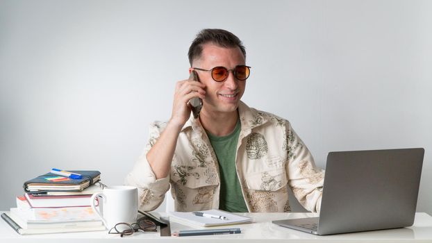 A student or employee talks on a smartphone at their desk. High quality photo