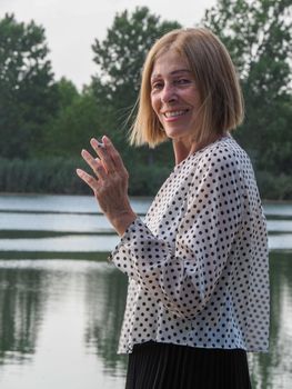 female pensioner having fun and smoking a cigarette in a park - aging free and wellness concept