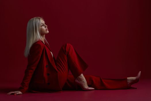 Portrait of a blonde woman in red dress on a red background