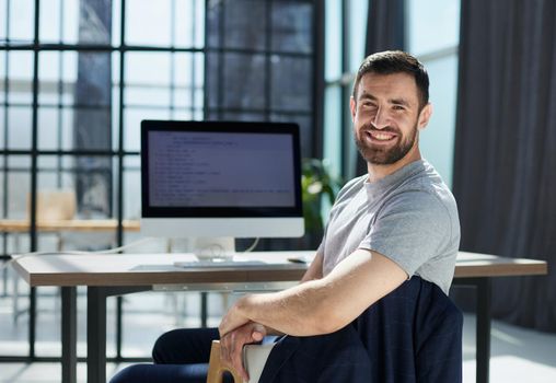 Portrait of confident businessman with laptop at desk in office