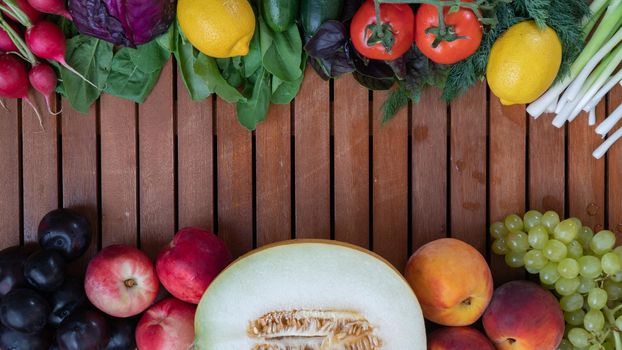 Fruits and vegetables mix in the form of a frame on a wooden background with space for inscription. High quality photo