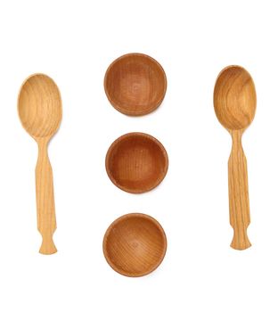 Empty wooden spoons and wooden bowls on a white isolated background, top view