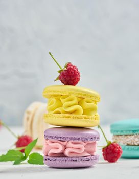 A stack of multicolored macaroons and red raspberries on a white background. delicious dessert