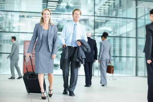 Business can take you around the world. Positive mature businesspeople arriving at an airport with their suitcases - Business Travel