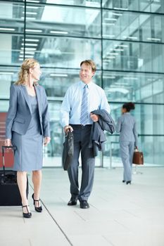 Heading out to a corporate conference. Smiling mature businesspeople arriving at an airport with their suitcases - Business Travel