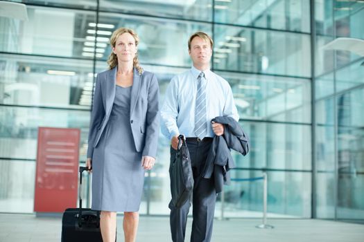 Heading to an important conference. Determined mature businesspeople arriving at an airport with their suitcases - Business Travel