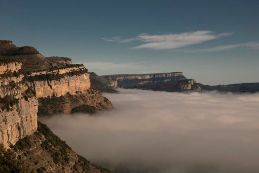 Landscape partially covered by a layer of fog under a blue sky in Tavertet town in Catalonia