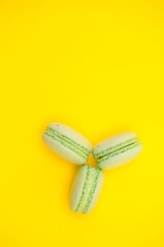 Top view of three sweet macaroons over yellow background. Luxury dessert