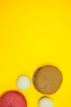 Top view of different macaroons color over yellow background. French dessert