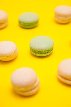 Little green tea macaroons and vanilla macaroons over yellow background