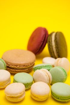 Tasty different macaroons flavour on yellow background. Sweet dessert